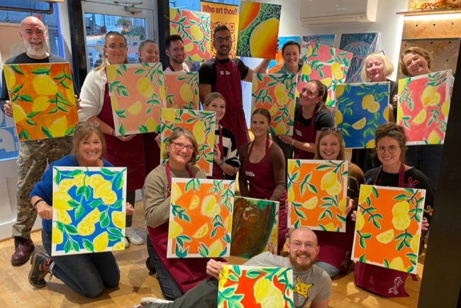 Happy painters at Pinot & Picasso, holding up their artwork.